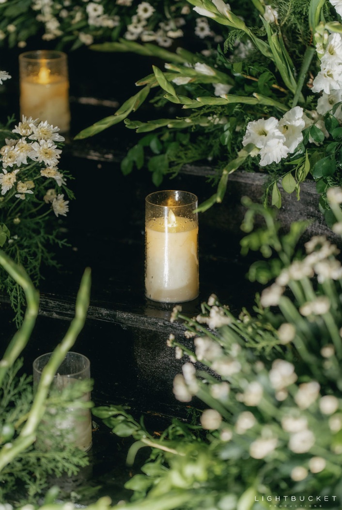 Candles in glass with white chrysanthemums, gladioli and ferns dressing dark stone steps at a Bangalore wedding