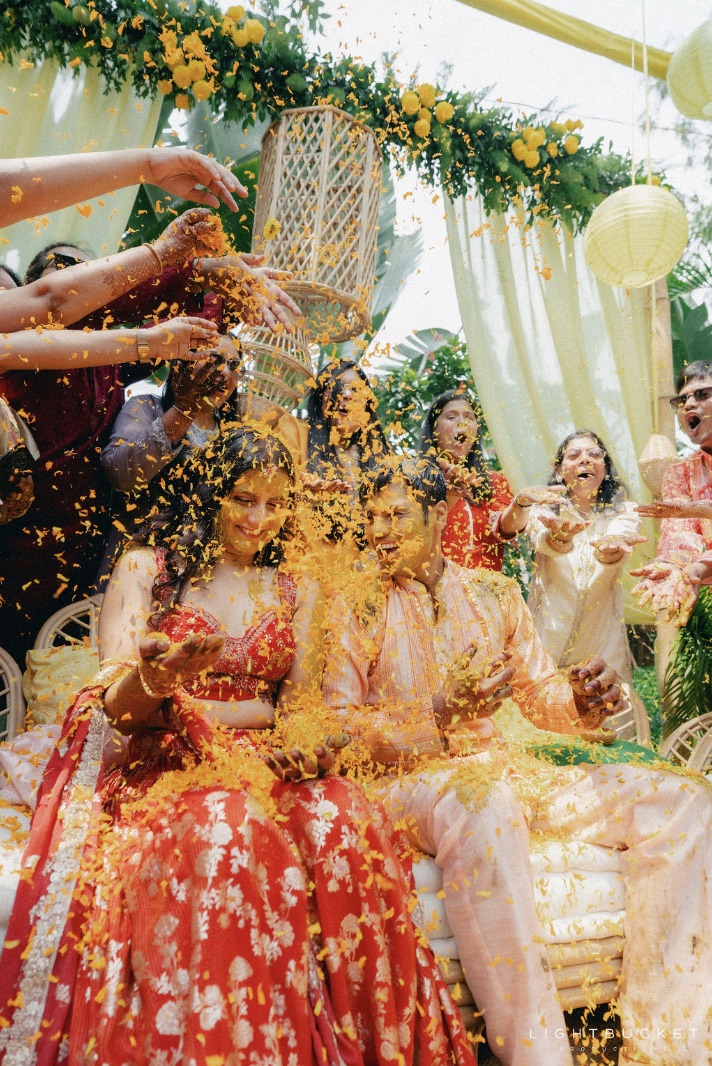 Family showering marigold petals on Mahak and Abhishek during the haldi ceremony at Nature Knots Bangalore