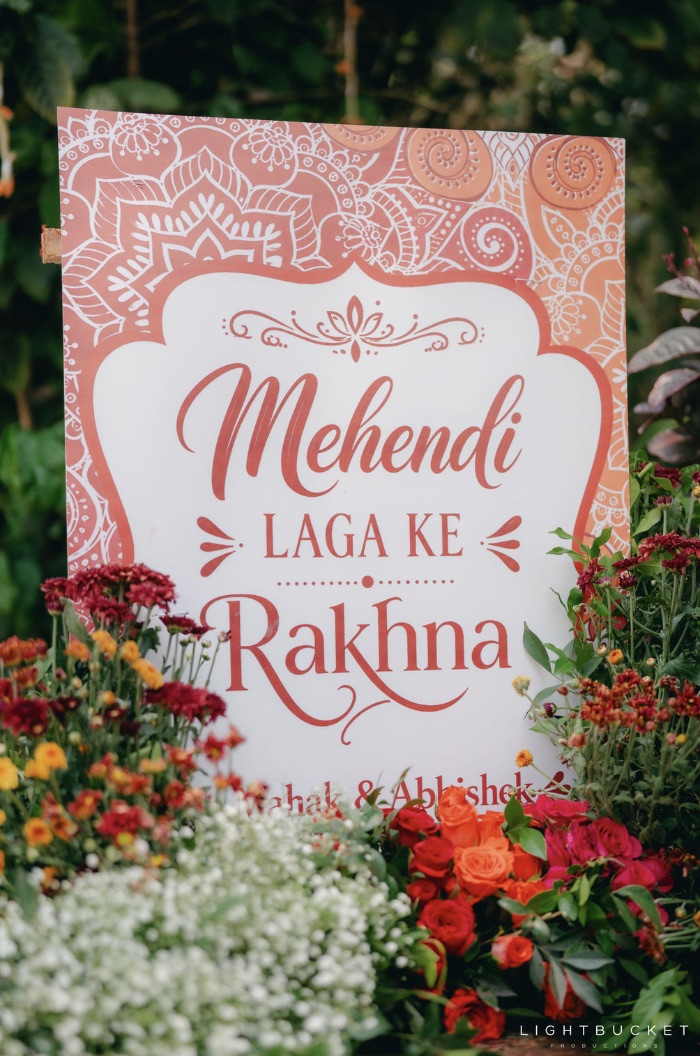 Mehendi Laga Ke Rakhna sign board rising from maroon and orange flowers at a mehendi at Nature Knots Bangalore