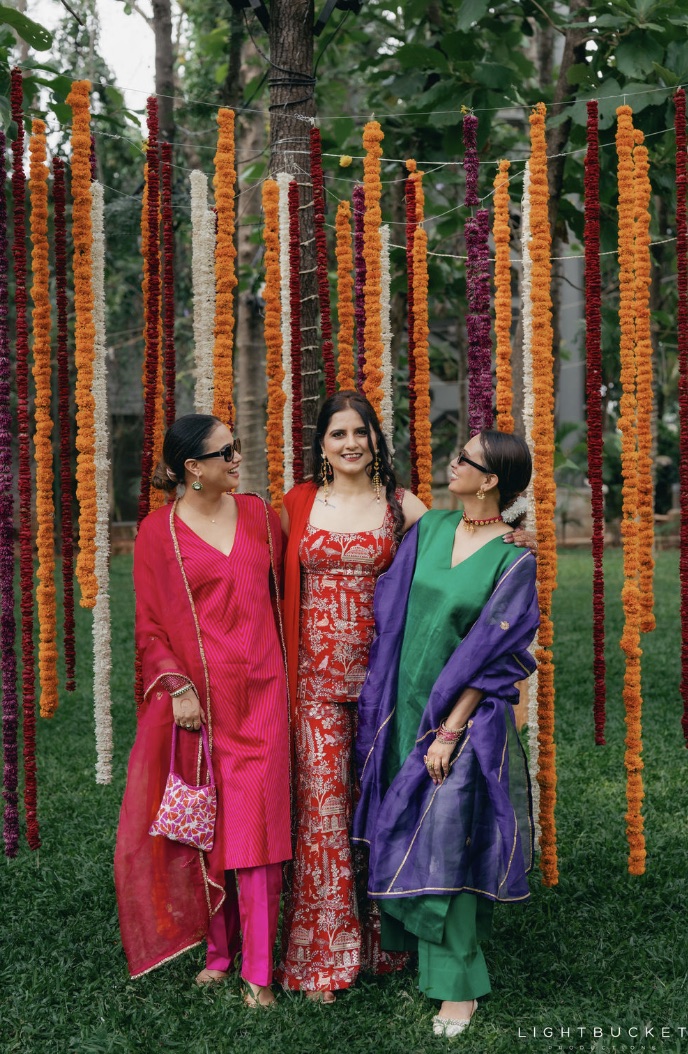 Backdrop of hanging marigold, jasmine and amaranthus garland strings between trees at Nature Knots Bangalore