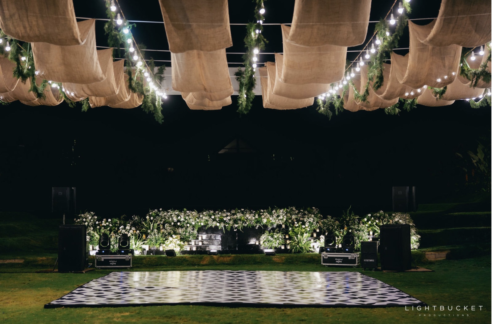 Black and white checkered dance floor facing a white floral and candle stage under a jute canopy at Nature Knots Bangalore