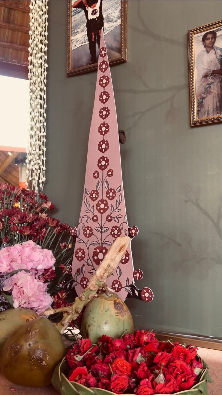 Tender coconuts and a woven leaf plate filled with loose red roses at the base of the painted kalash cutout