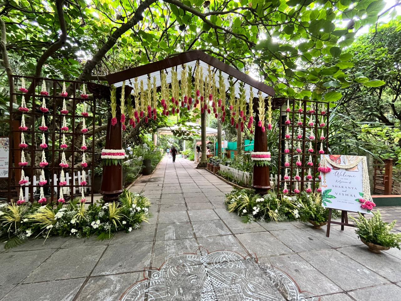 Garland-hung wedding entrance gate with kolam on the stone path at MG Magnus Miraya Greens Bangalore