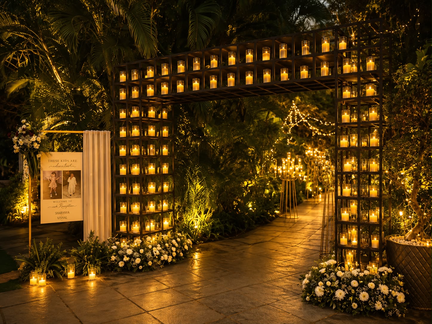 Candle wall entrance structure with glass-shielded candles and white chrysanthemum beds at a Bangalore garden wedding reception