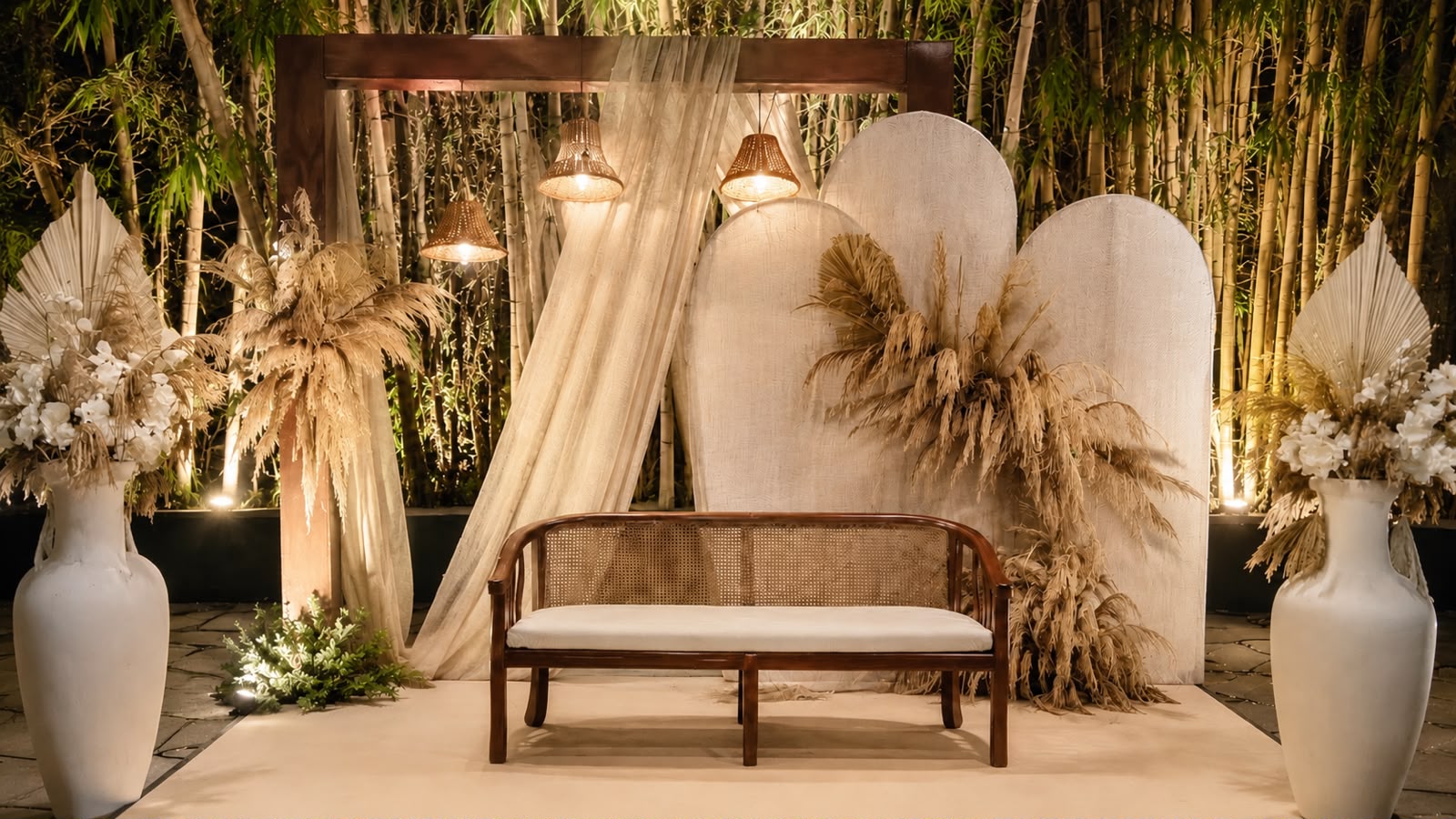 Pastel photo corner with cane bench, arched boards, dried palm arrangements and cane pendant lamps at MG Magnus Bangalore