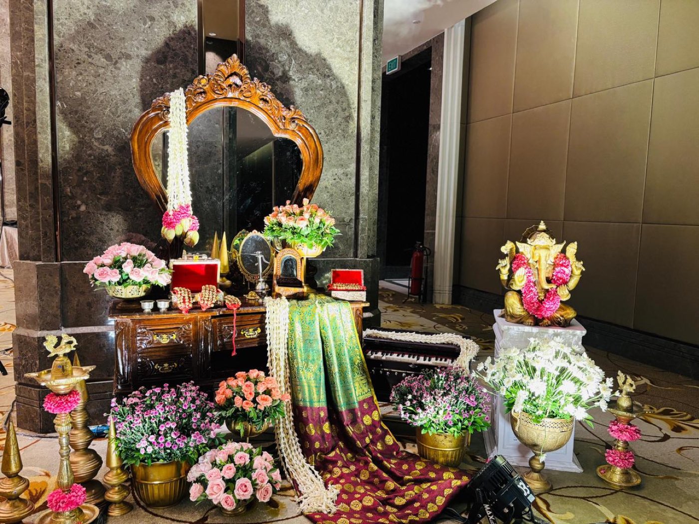 Carved mirror console with the half saree displayed on the drape, brass Ganesha and floral urns alongside