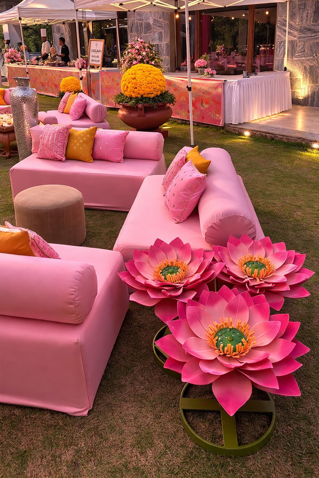 Giant pink lotus props beside pink lounge seating with buffet counters behind at Amita Rasa mehendi