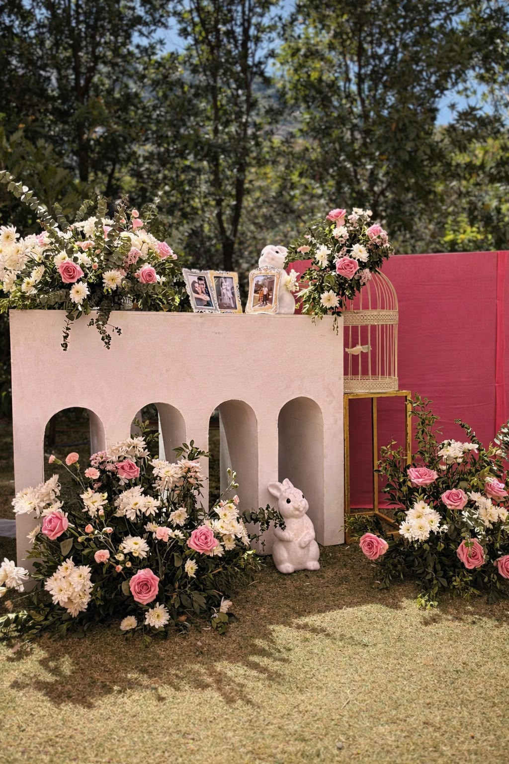 Wide view of the memory corner with white arched console, pink fabric panel and rose bushes at Amita Rasa, Nandi Hills near Bangalore