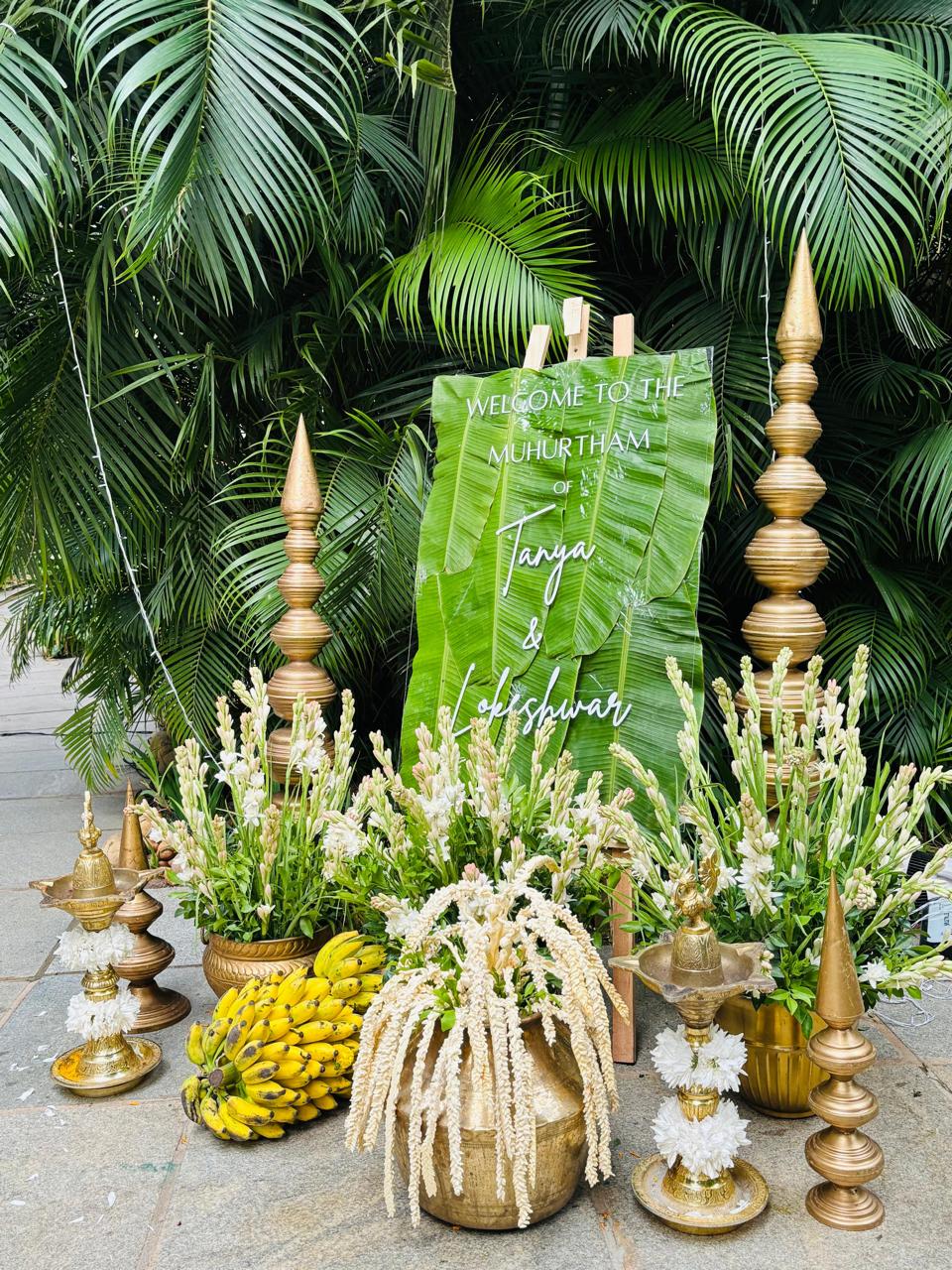 Muhurtham welcome board for Tanya and Lokeshwar lettered on real banana leaves with brass kalash towers and bananas at MG Magnus