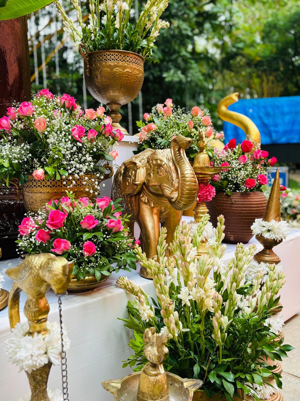 Gold brass elephant among pink rose and baby's breath arrangements on the mandap steps at a Bangalore garden wedding