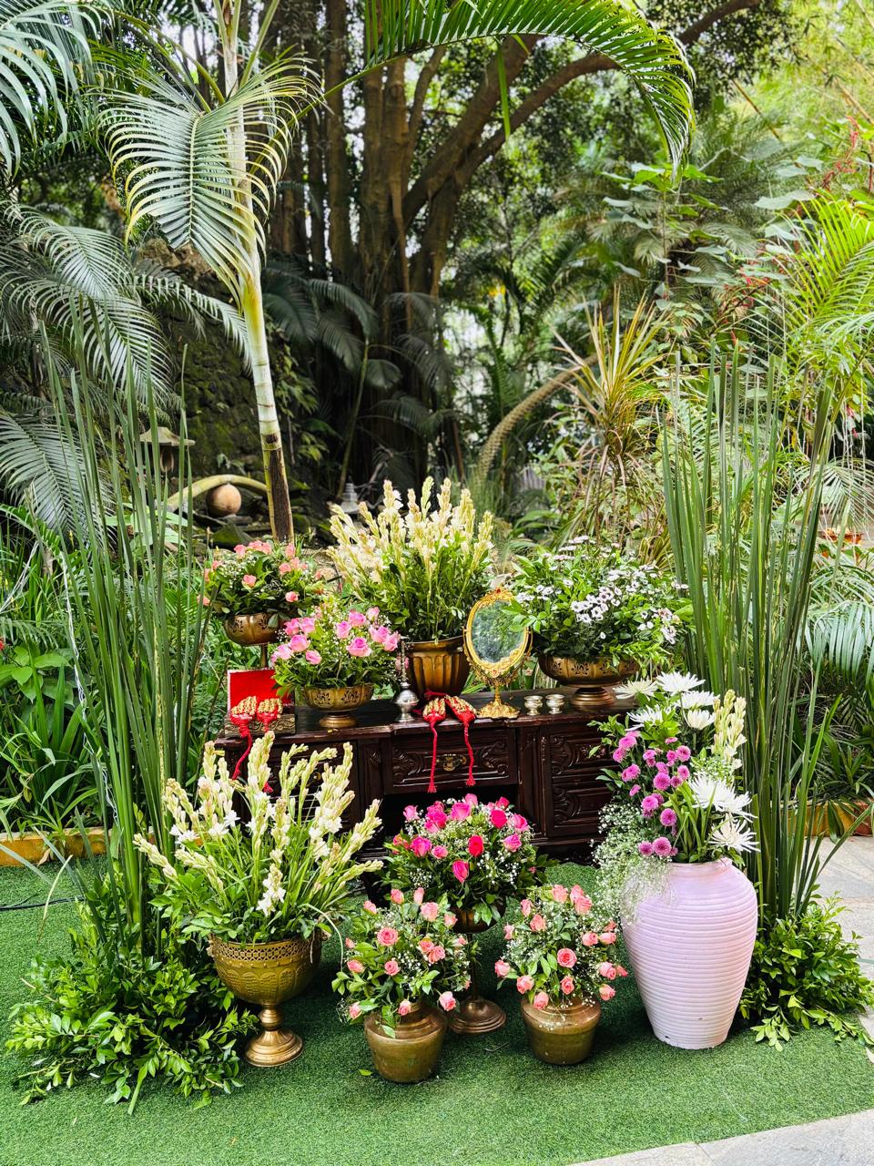 Vintage wooden vanity ritual corner with roses, gold mirror and red shagun pouches set in the garden at MG Magnus Miraya Greens