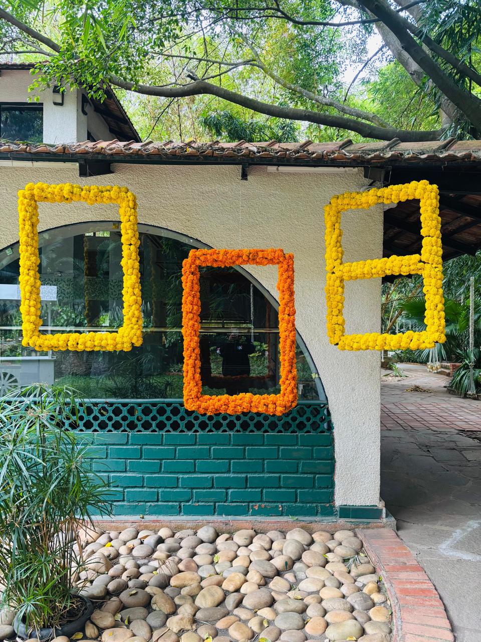 Yellow and orange marigold photo frames hanging in front of an arched window at a haldi ceremony in Bangalore