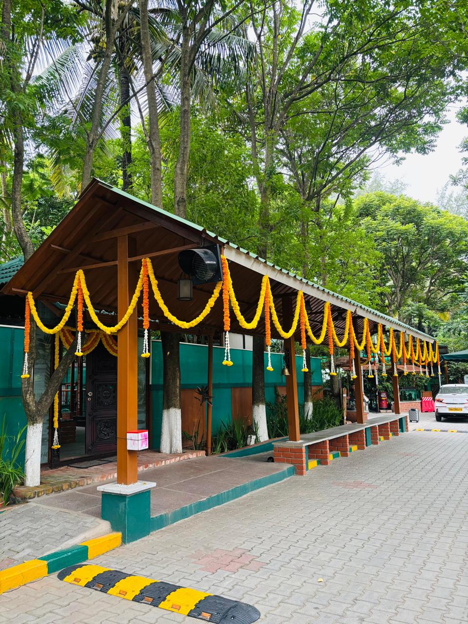 Long covered walkway swagged with yellow and orange marigold garlands at MG Magnus Miraya Greens Bangalore