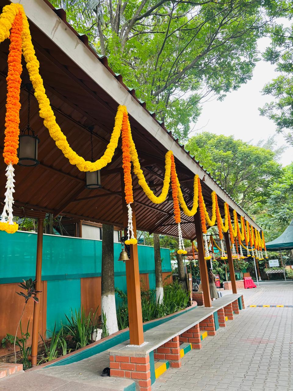 Marigold garland swags with hanging temple bell and tuberose drops along a walkway at a Bangalore wedding