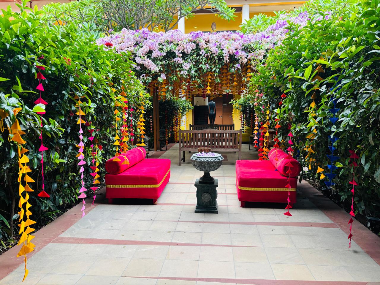 Mehendi courtyard with hot pink daybeds and multicolour felt bunting strings at MG Magnus Miraya Greens Bangalore