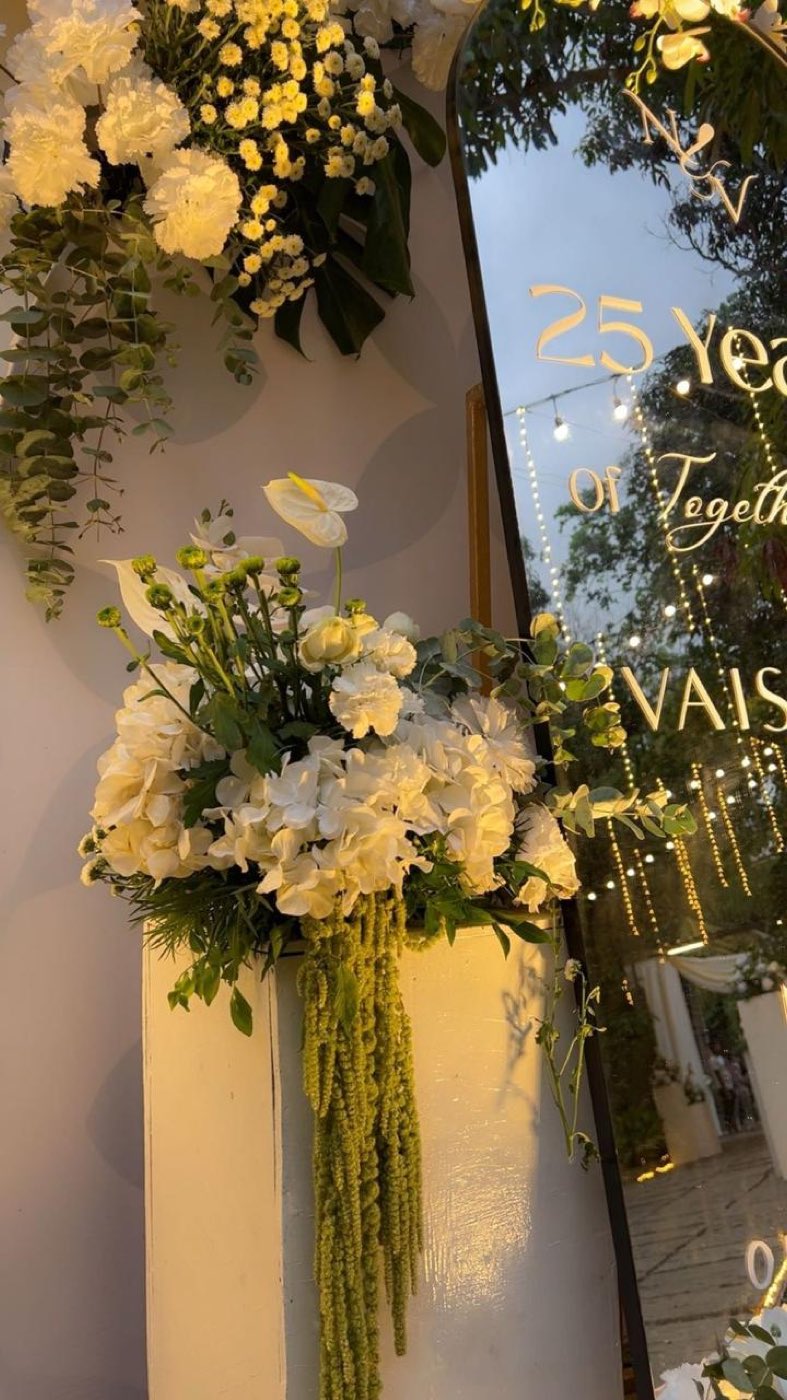 Detail of white hydrangea, anthurium and hanging amaranthus beside the mirrored anniversary signage